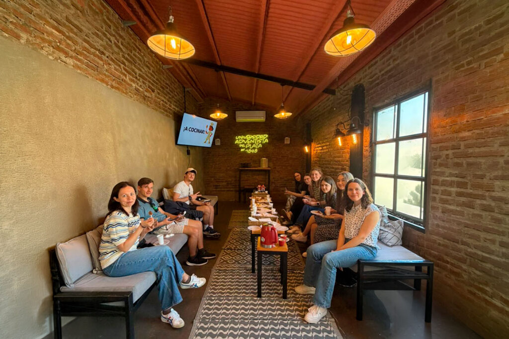 Docente y alumnos compartiendo una dinámica social con alimentos típicos de Argentina en El Patio del campus UAP.