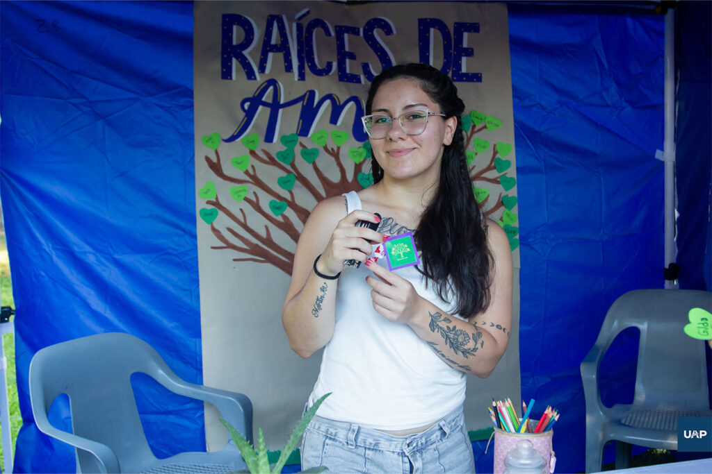 Estudiante de la Lic. en Psicopedagogía presentando el grupo voluntario "Raíces de Amor" en su stand.